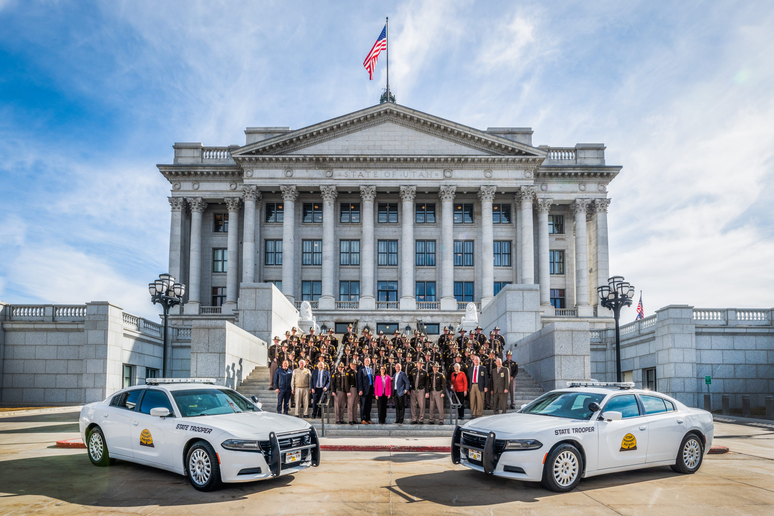A group of troopers stand with the Governor and Lt. Governor on the west side of the state capitol building.