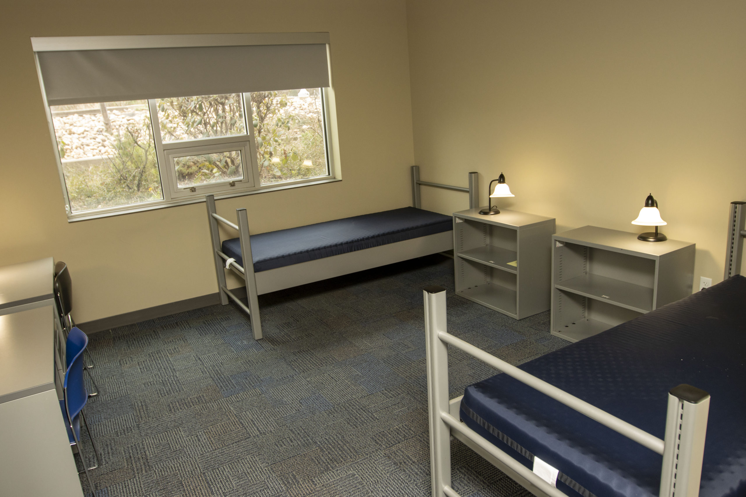 Dorm room at POST has two bunch beds, two desks and two book cases.