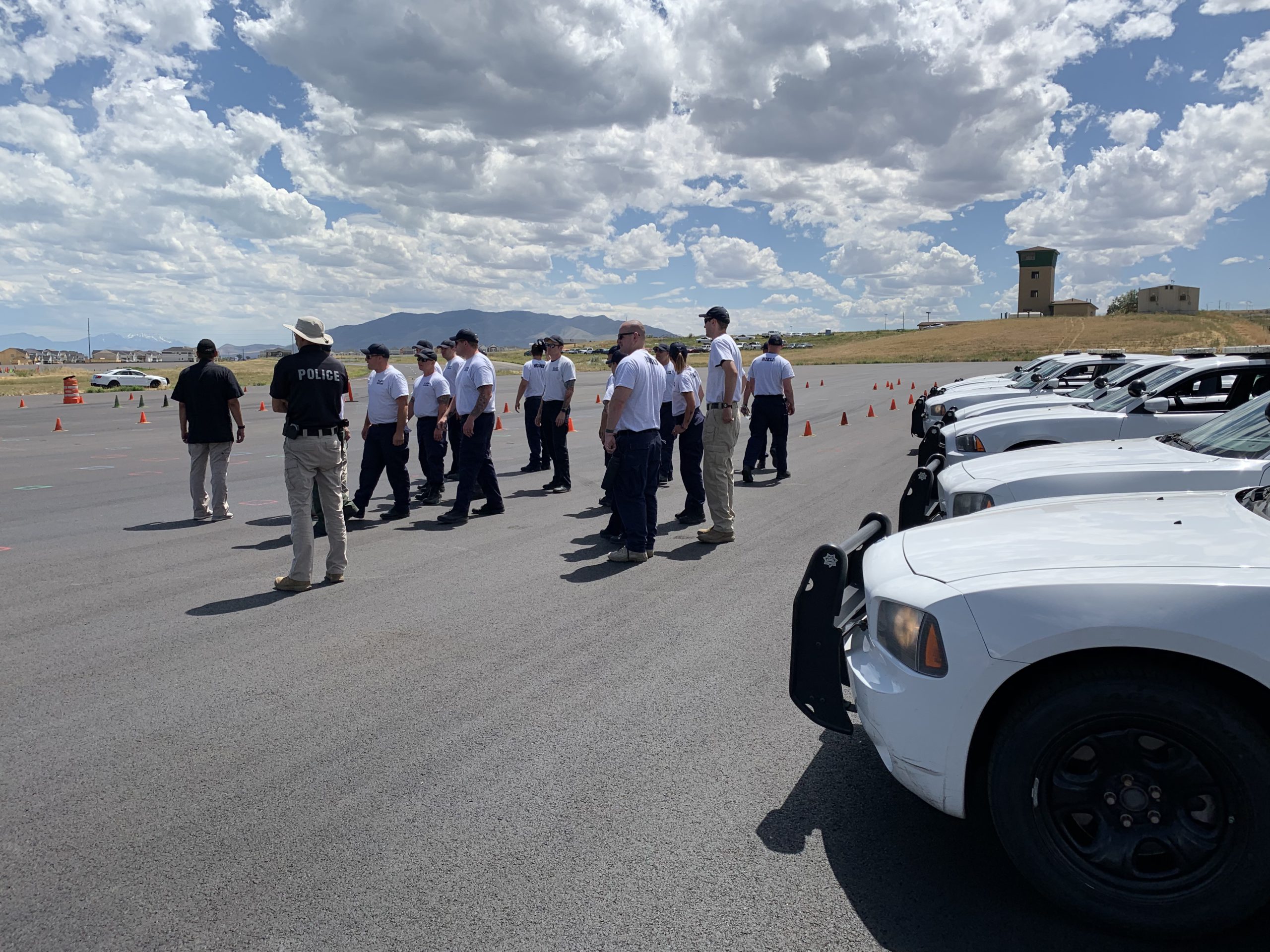 Cadets stand in a group at the EVO track with Chargers in the foreground.