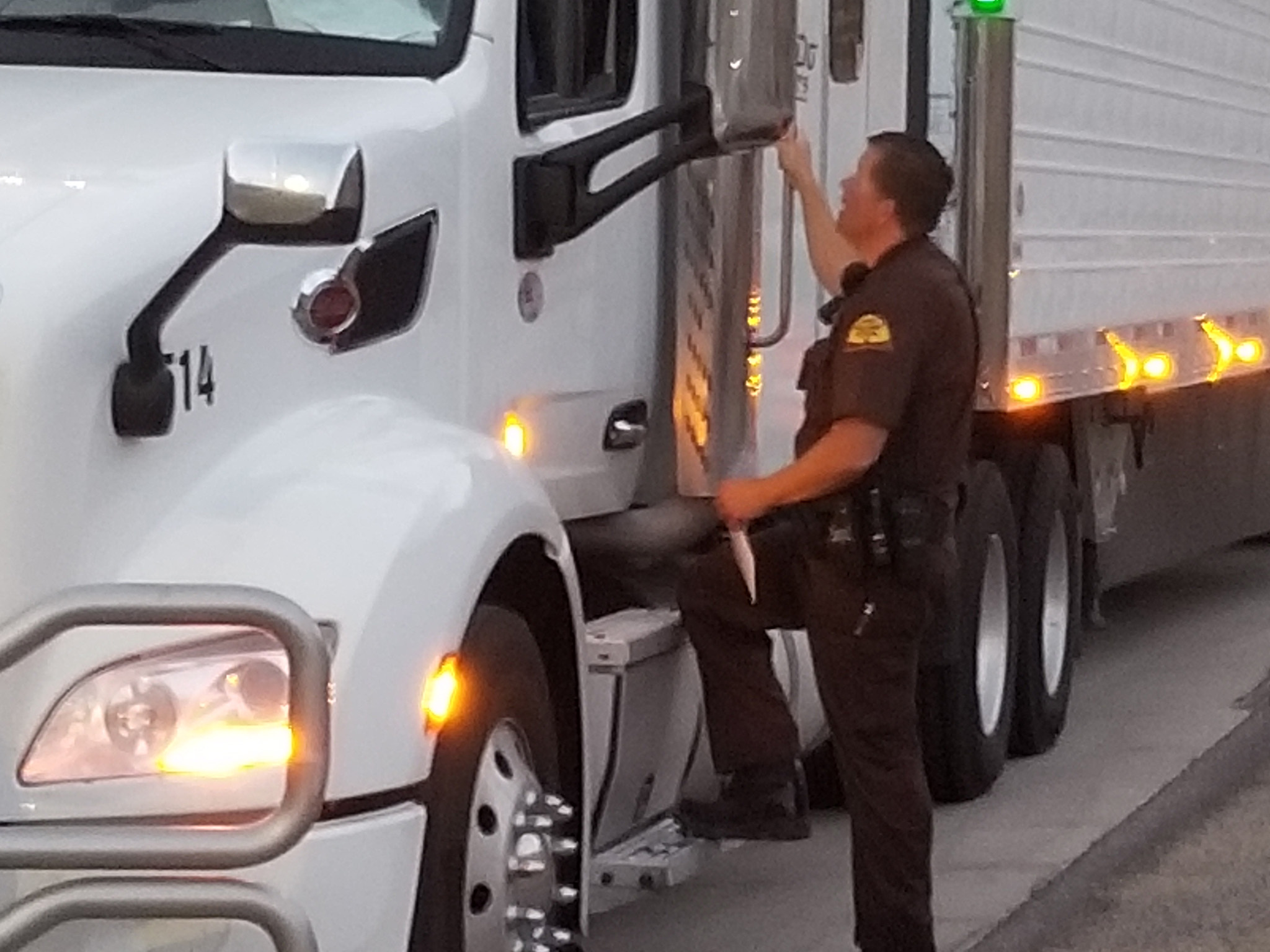 A UHP Trooper stands by the cab of a semi truck.