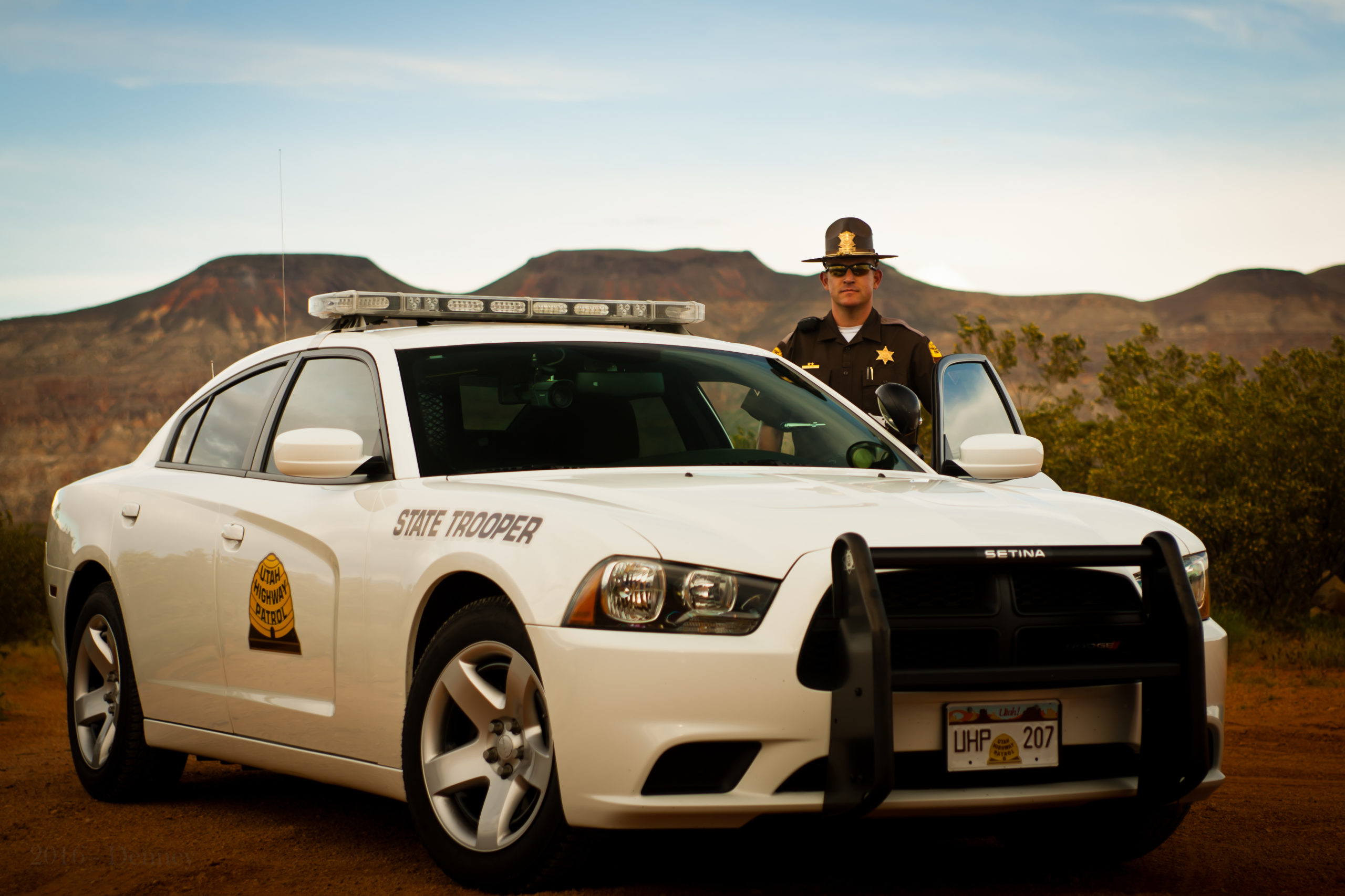 A UHP Trooper stands beside his charger.